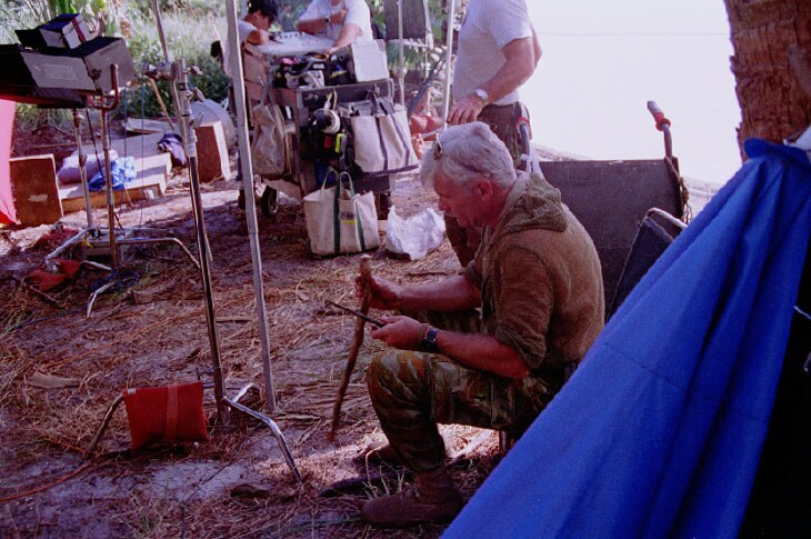Dale Dye: Between shots, Dale Dye, the film’s military advisor, works on his carving.