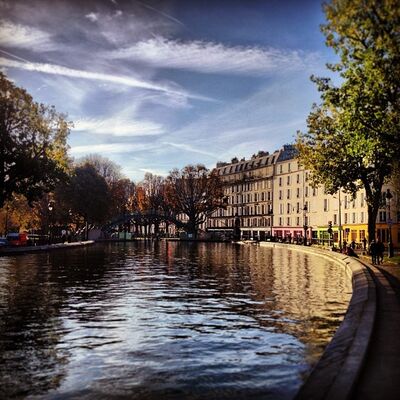 The Canal Saint-Martin curving between autumn trees and cream-colored apartment buildings