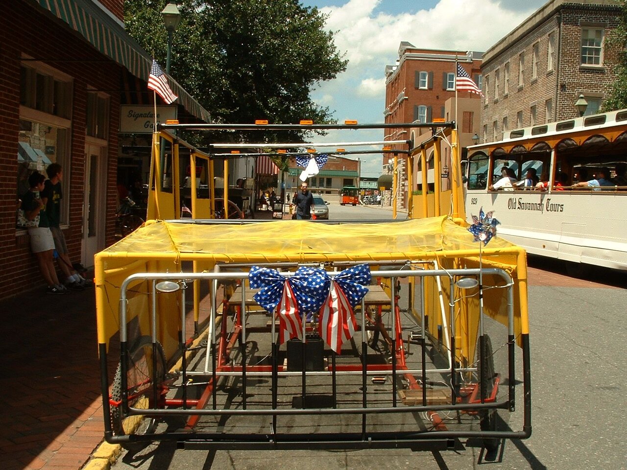 The front of the Green Hummer, decorated with flags and a stars-and-stripes bow, next to an Old Savannah Tours trolley