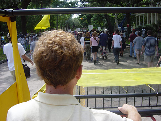 A rider looking over the front of the Green Hummer at a street full of marchers