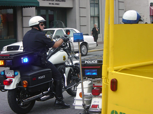 A motorcycle police officer riding alongside the Green Hummer