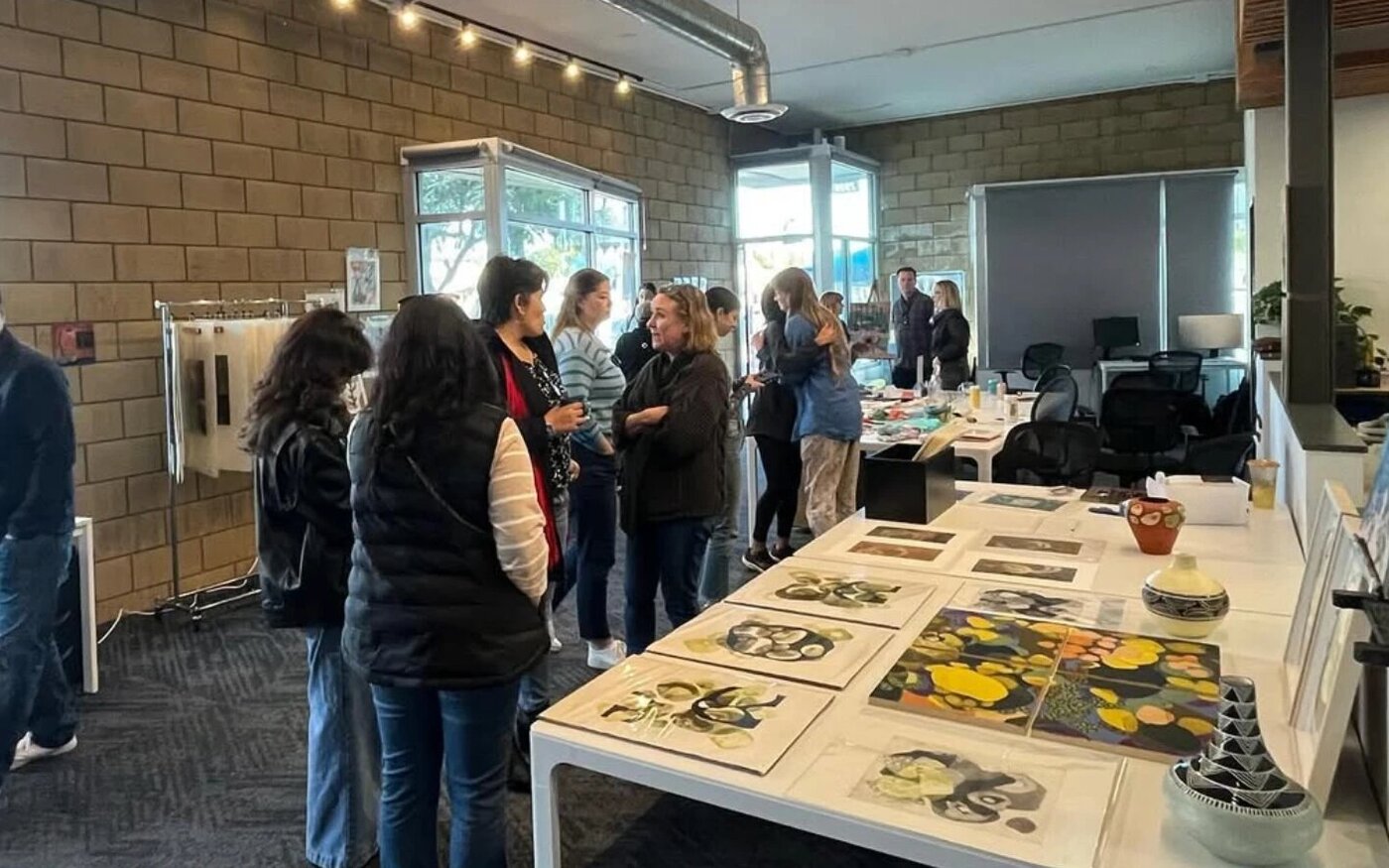 Guests at a community event looking at artwork laid out on a long table
