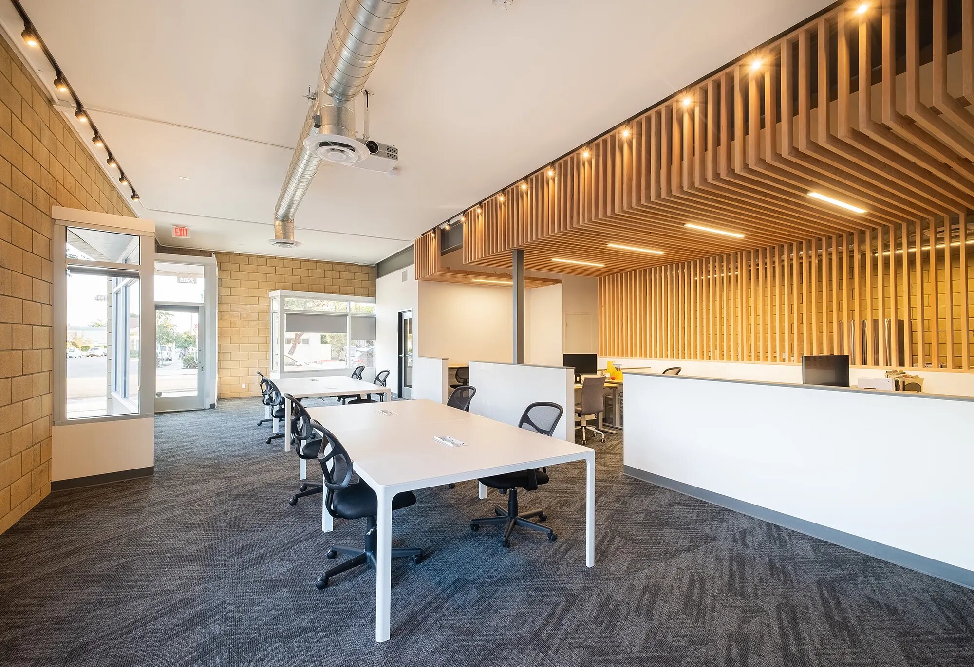 The Ivy Street coworking space, with long white desks, cinder-block walls, and a slatted wood ceiling