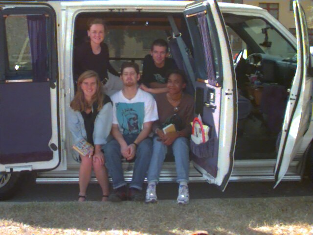 The five Lost in America travelers sitting in the open side door of their van
