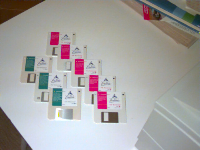 A dozen AOL install floppy disks fanned out on a white table