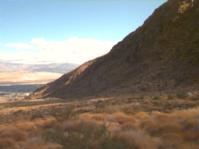 A mountainside above the desert at sunset