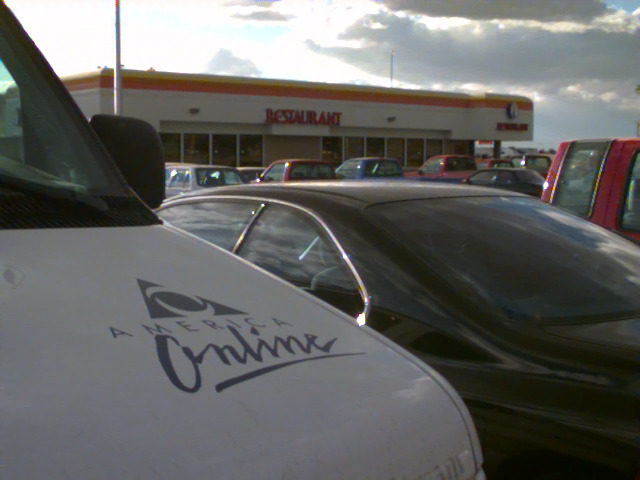 A gas station, with the Lost in America logo on a car’s hood in the foreground