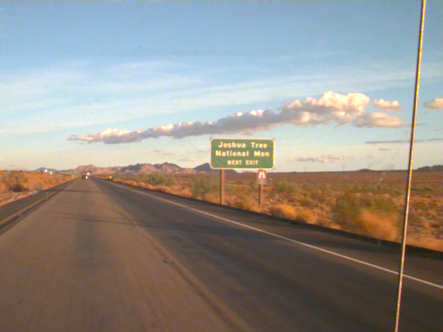 A straight desert road with a sign ahead