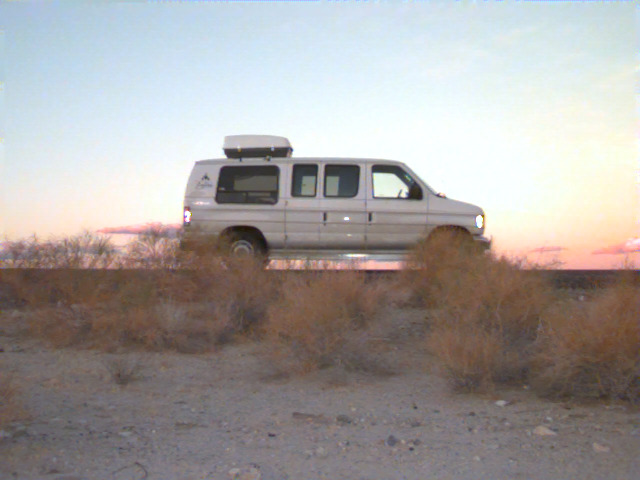 The van parked in the desert at sunset